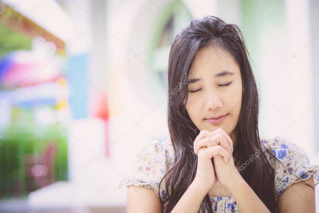 Beautiful Asian woman praying; Blur background; Vintage tone