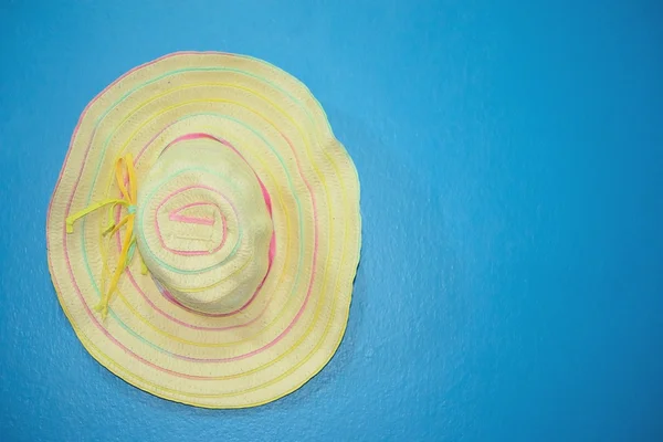 Yellow hat with ribbon on blue — Stock Photo, Image