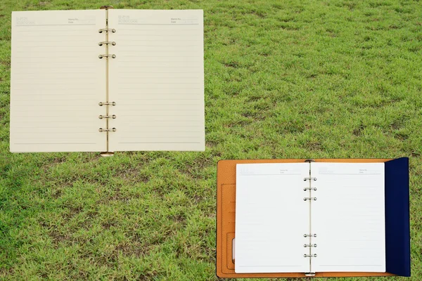 Livro de notas sobre fundo de grama verde — Fotografia de Stock