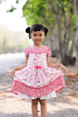 Asyalı çocuk doğa arka plan üzerinde kırmızı elbise göster