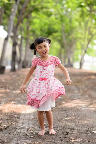 Asian kid show her red dress and dancing in the garden — Stock Photo, Image