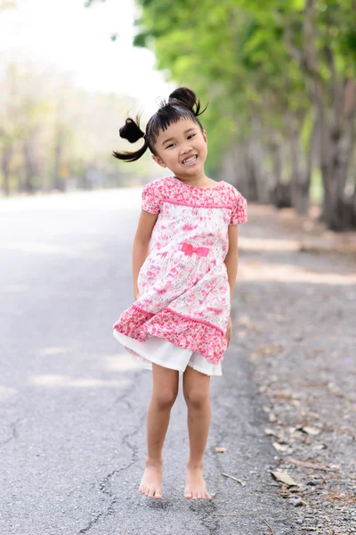 Asiatiska barn visar hennes röda klänning och dans i trädgården — Stockfoto