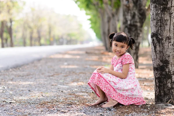 Kid stående med röd klänning på trädgård bakgrunden — Stockfoto