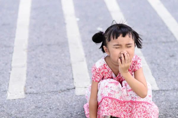 Ребенок чихает на фоне асфальтовой дороги — стоковое фото