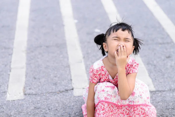 Ребенок чихает на фоне асфальтовой дороги — стоковое фото