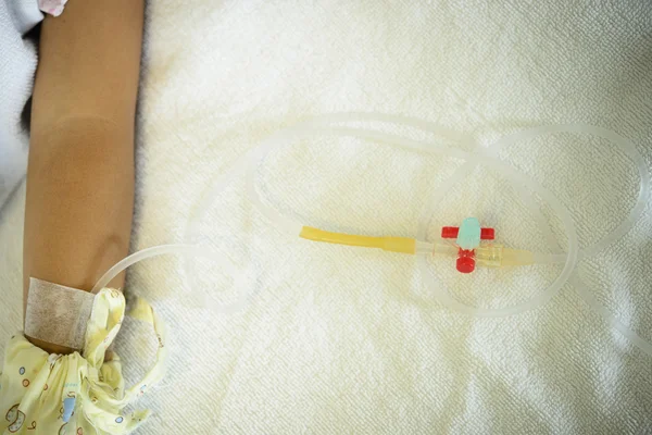 Tube de solution saline avec bras patient sur le lit — Photo