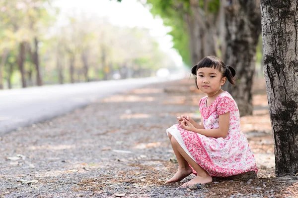 Portrait d'enfant avec robe rouge assis sur le sol Image En Vente