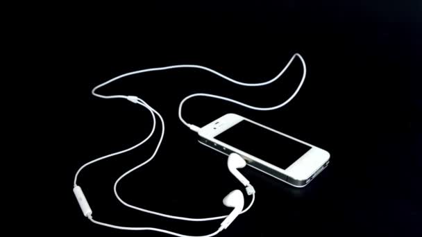 Telefon mit Kopfhörer auf schwarzem Material 4k — Stockvideo