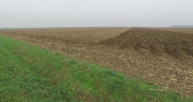 Small tractor in distance plowing field, preparing ground for winter time.