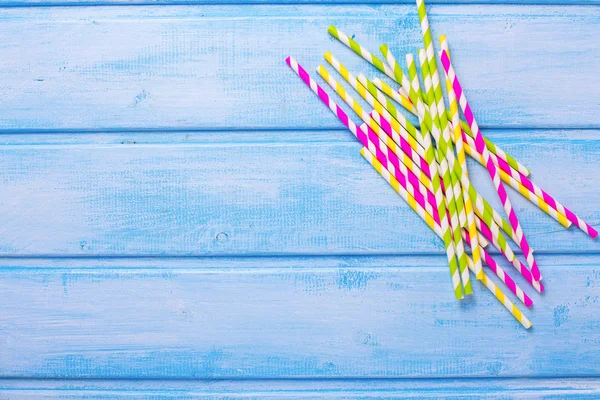 Paper straws on blue wooden background