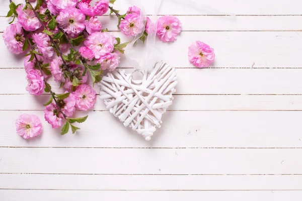 Pembe çiçekler ve beyaz dekoratif kalp — Stok fotoğraf
