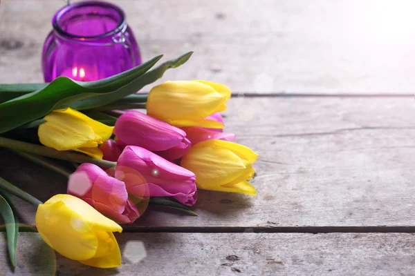 Spring tulips and violet candle — Zdjęcie stockowe