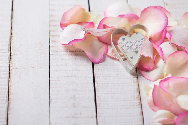 Corazón sobre pétalos sobre fondo de madera — Foto de Stock