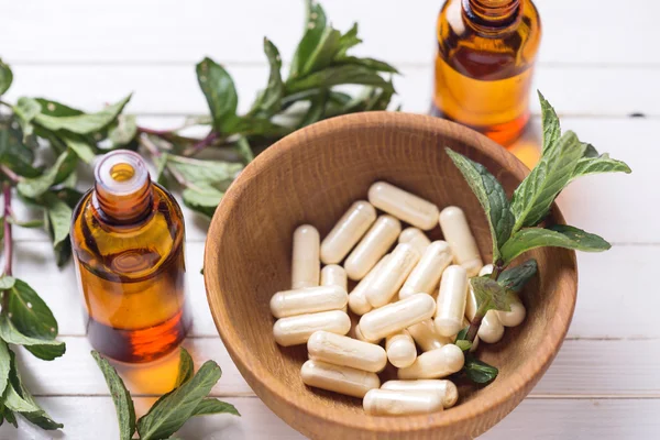 Pills  in bowl and leaves — Stock Photo, Image