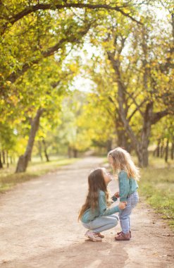 Sonbahar parkında oynayan iki tatlı kız kardeş..