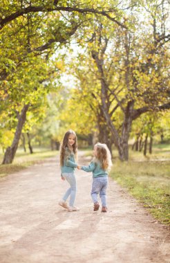Sonbahar parkında oynayan iki tatlı kız kardeş..