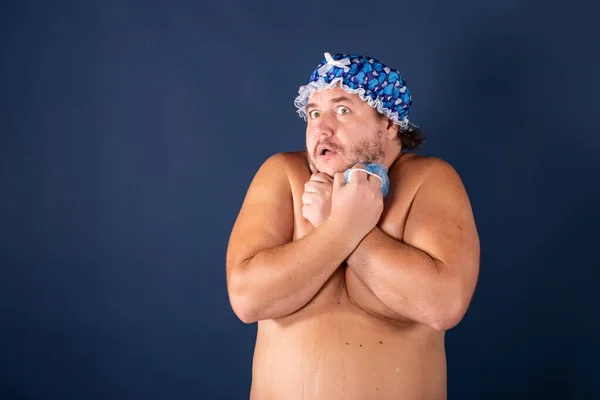 Funny fat man in blue cap sing in the shower