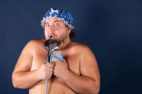 Funny fat man in blue cap sing in the shower