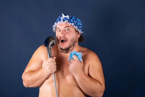 Rolig fet man i blå mössa sjunga i duschen Stockbild