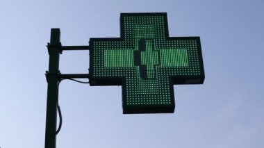 İtalya, Bologna 'da açık yeşil haç işareti. Neon ışığı yanıp sönüyor ve görüntüyü değiştiriyor. 