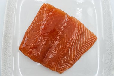 Beyaz bir tabakta taze çiğ somon balığı filetosu.