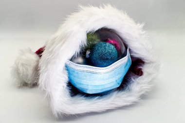 Noel Baba şapkası ve tıbbi maske beyaz arka planda izole edilmiş. Covid-19 konseptiyle Mutlu Noeller.