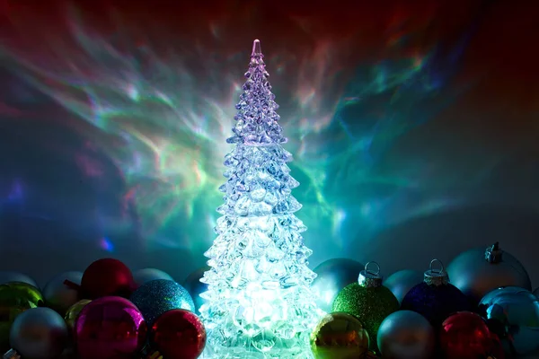 Illuminated Christmas tree sparkling lights. Traditional Christmas ornament on multicolored blur background