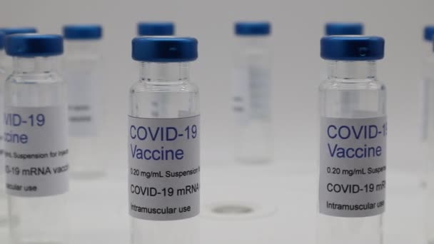 Átlátszó, üres injekciós üveg Covid-19 Vakcina címkével, forgó kijelzőn.