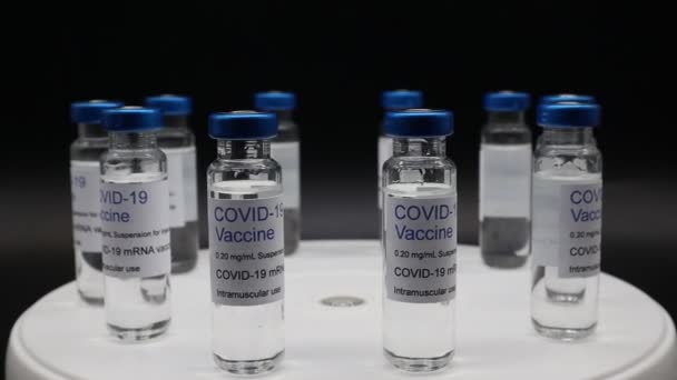 带Covid 19疫苗的玻璃瓶在黑色背景上隔离的旋转显示屏上 — 图库视频影像