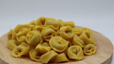 Dönen ekrandaki çiğ tortellini beyaza izole edilmiş. Geleneksel İtalyan makarnası