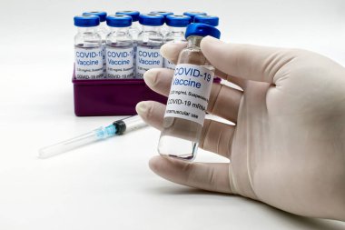 Doktor, elinde bir şişe Covid-19 aşısı tutan plastik eldiven verdi..