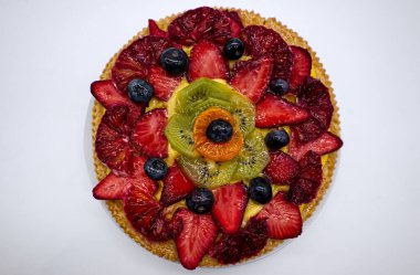 Fresh fruit tart with strawberries, kiwi and orange, isolated on white background top view