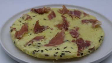 Jambonlu omlet ve beyaz tabak şeklinde soğan.