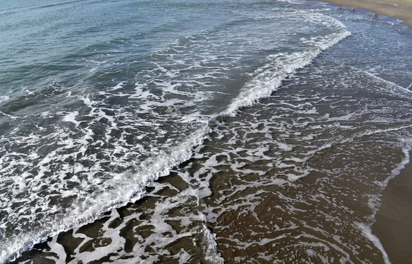 Deniz dalgaları kıyıya vuruyor. Beyaz deniz köpüğü.