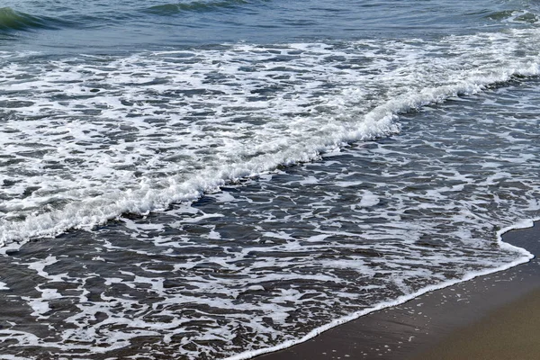 Deniz dalgaları kıyıya vuruyor. Beyaz deniz köpüğü. Yukarıdan görüntüle.