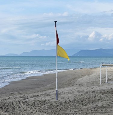 İtalya 'nın Forte dei Marmi sahilinde kırmızı ve sarı uyarı bayrağı.