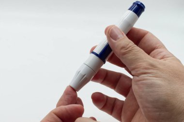 Diyabet hastası kadın glukometre kullanmadan önce tükenmez kalem kullanıyor, beyaz arka planda izole edilmiş. Diyabet teşhisi