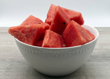 Tahta masada beyaz bir kasede karpuz dilimleri. Taze meyve.