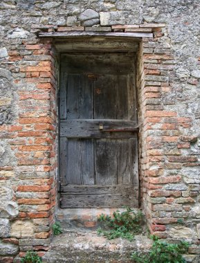 Serravalle Şatosu, Bolonya, İtalya 'da yıkık dökük tuğla bir duvarda eskimiş ahşap bir kapı..