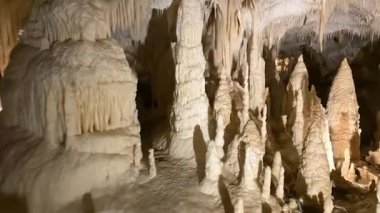 Majestic underground cave displaying intricate natural stalactite and stalagmite formations, a geological wonder.
