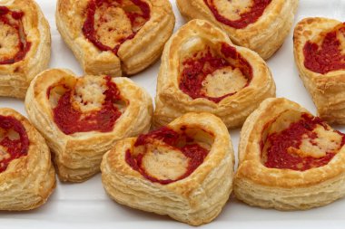 Lezzetli kalp şeklindeki puf böreği aperatifleri lezzetli domates sosu içeren hafif ahşap bir yüzeyde güzelce düzenlenir..