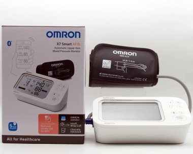 Bologna - İtalyan- 9 Aralık 2025: Omron x7 akıllı afib otomatik üst kol basıncı monitörü manşet ve perakende paketleme beyaz arka planda izole edildi.