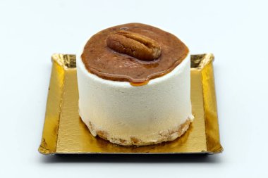 Kremalı bireysel silindirik kremalı tatlı zarif bir şekilde fındık ve küçük altın tepside zengin bir karamel jölesiyle sunuluyor..