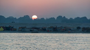 Varanasi - Hindistan - 21 Şubat 2025: Varanasi, Hindistan 'da geleneksel çadır ve siluetlerle Ganj Nehri üzerinde altın gün batımı.