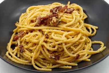 Klasik İtalyan spagettisi alla carbonara yanında gevrek guanciale ve kremalı yumurta sosu..