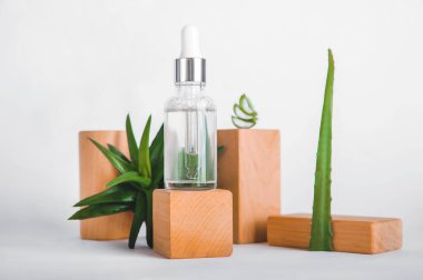 Ahşap blok podyumda pipetli serum ve aloe vera. Doğal malzemelerden yapılmış cilt bakım ürünleri. Ön görünüm.