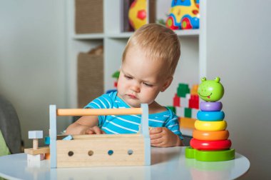 Yakışıklı çocuk anaokulunda ya da çocuk odasında ahşap oyuncaklarla oynar....