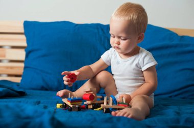 Mavi yataktaki küçük çocuk, yatmadan önce ahşap bloklarla yakın plan yap ve uzayı kopyala....