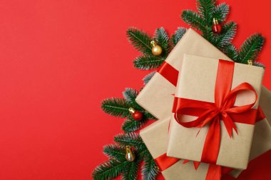 Kırmızı Kurdeleli Noel hediye kutuları ve Kırmızı Arkaplan 'da fidan dalları.