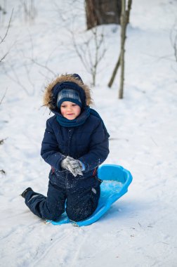 Küçük çocuk karlı ormanda kızakla kayarken dışarıda eğleniyor. Aktif çocukluk, mevsimlik açık hava eğlencesi, kış macerası, aile eğlencesi ve sağlıklı yaşam tarzı konsepti..